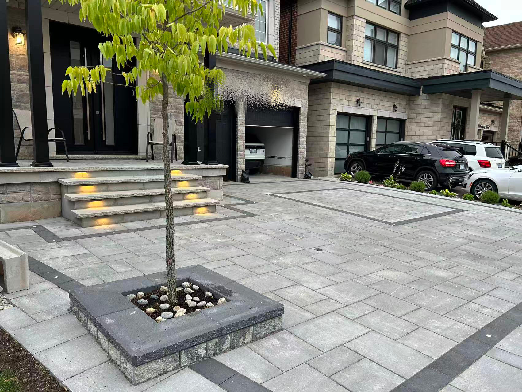 Luxury front driveway interlock with tree planter and lit steps