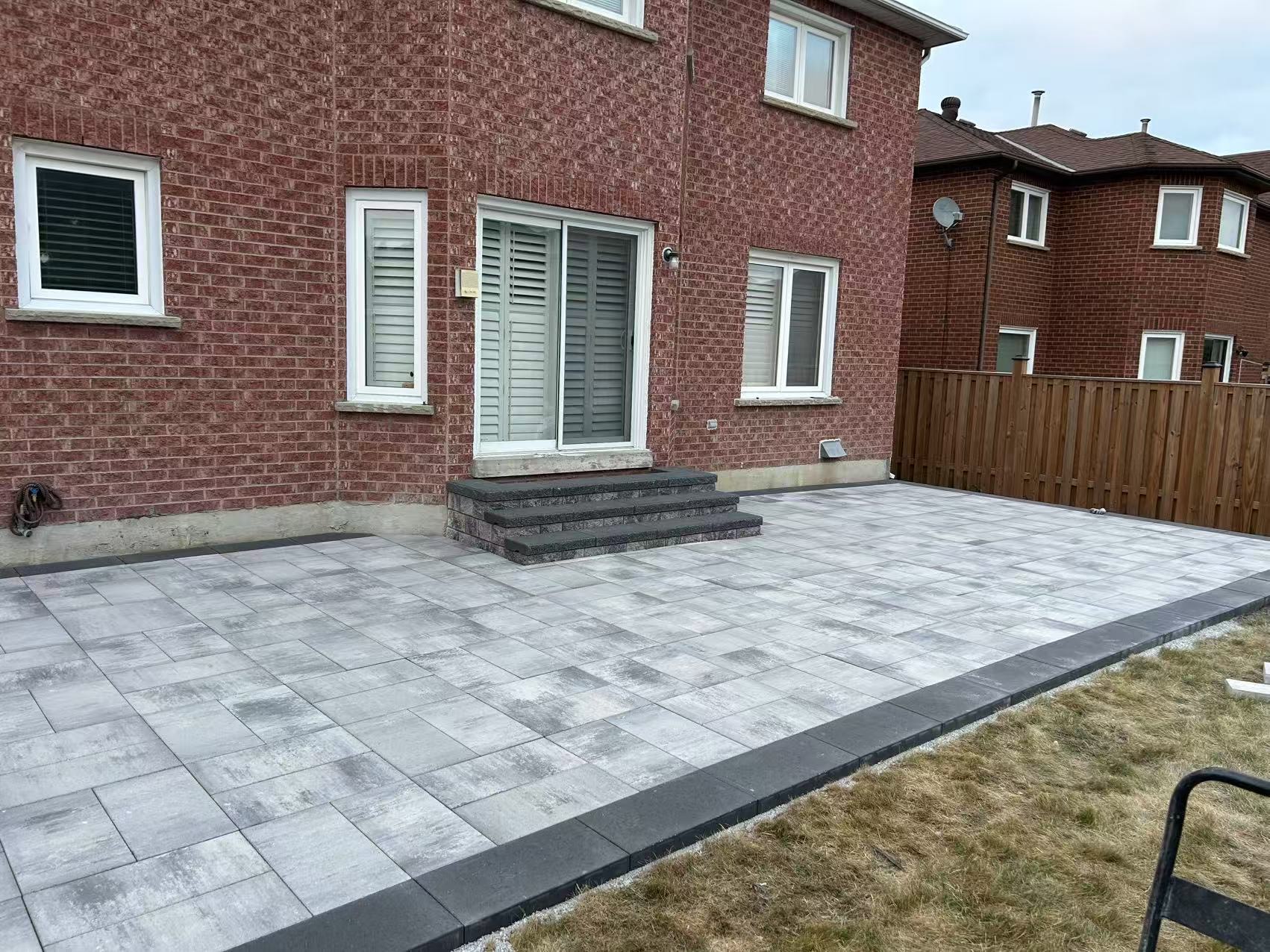 Backyard interlock patio with charcoal border and built-in steps