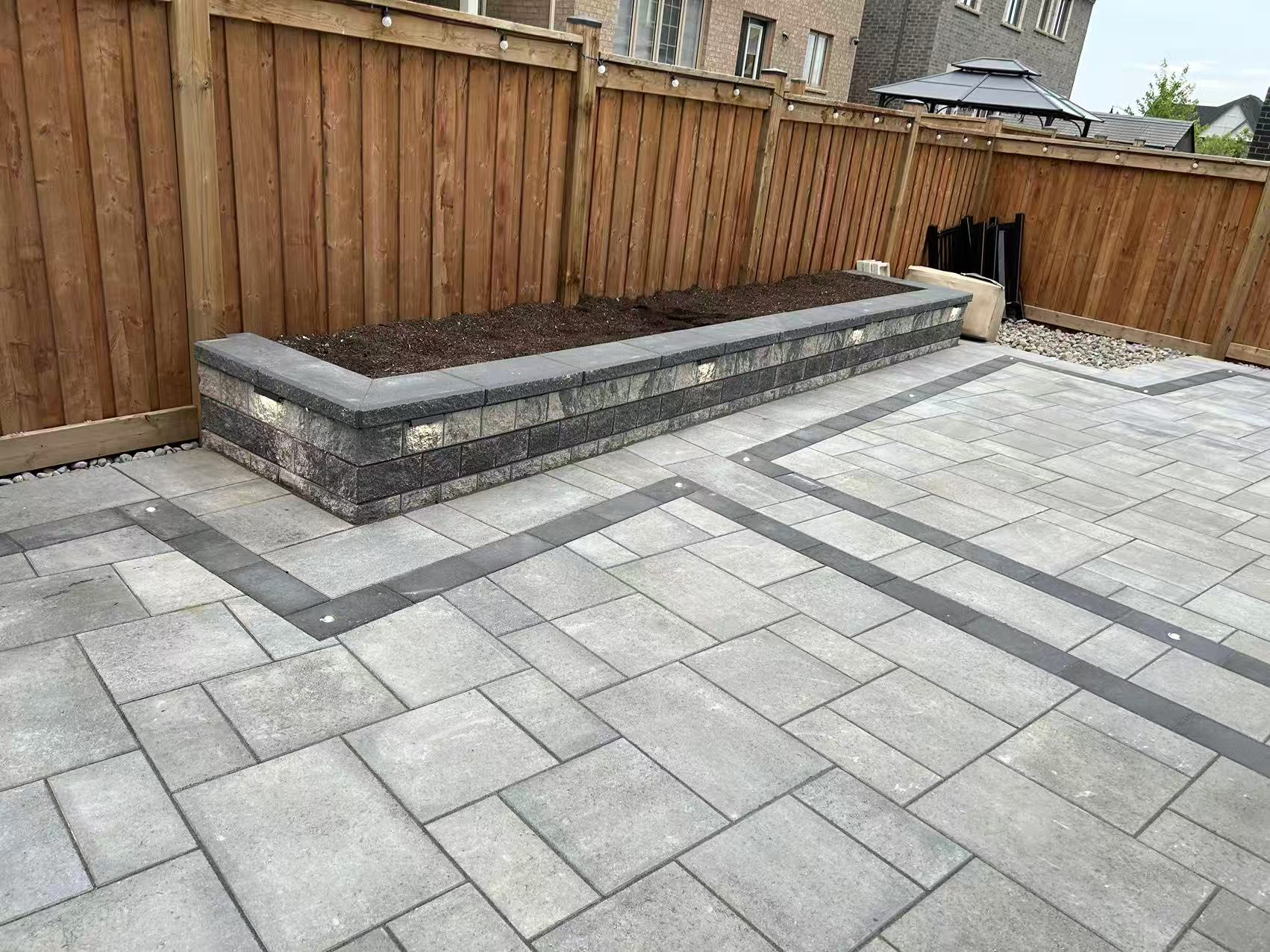 Backyard interlock with raised garden bed and cedar fence backdrop
