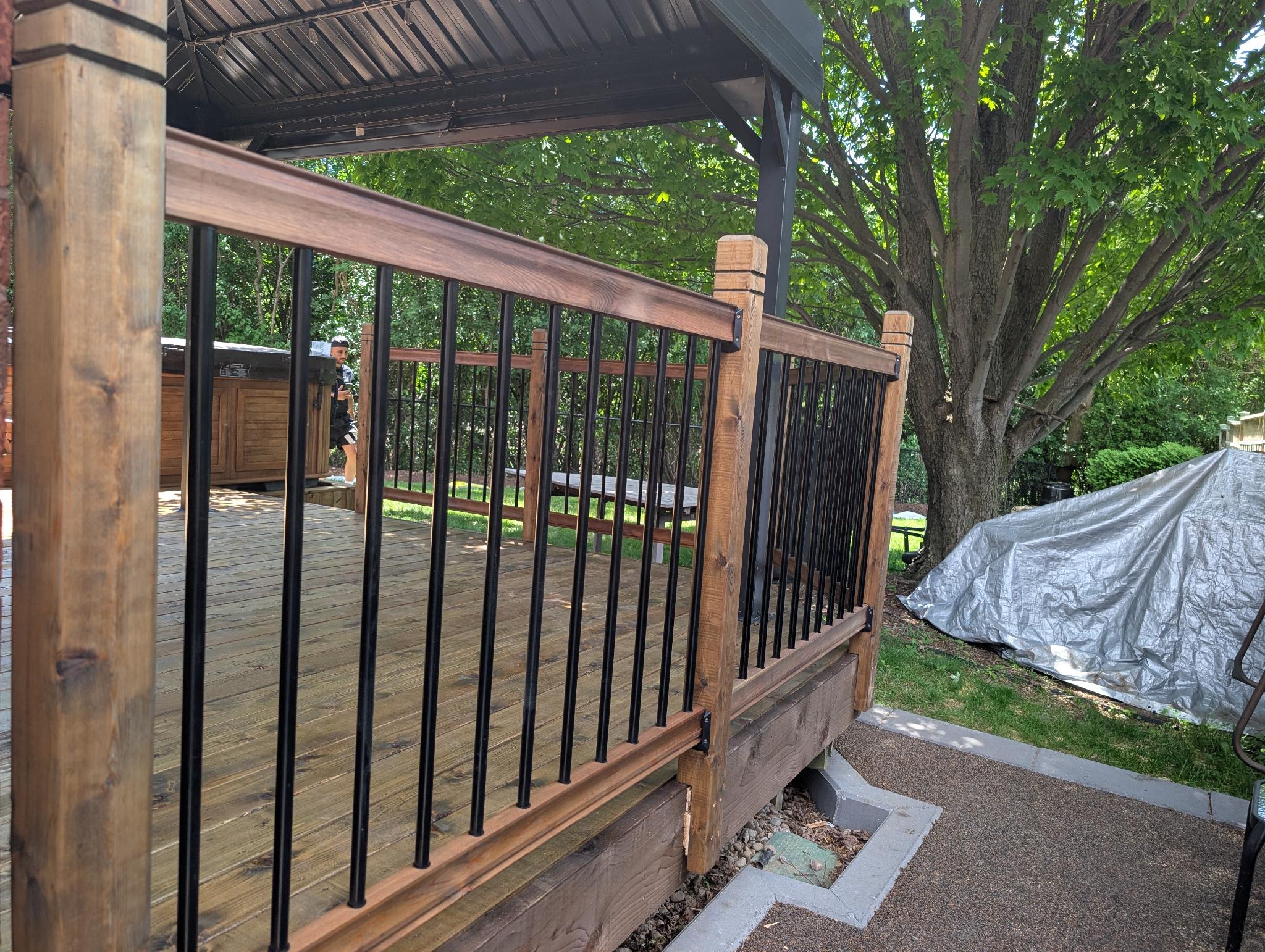Close-up stained railing with black metal balusters under gazebo
